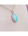 Necklace with a teardrop-shaped opal pendant on a person's neck.