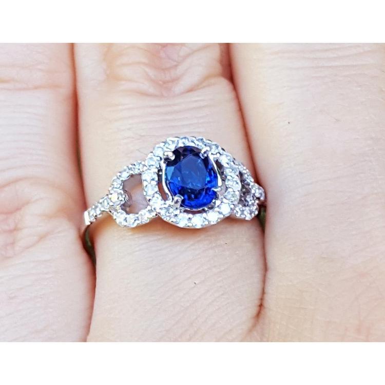 14k white gold ring with a natural blue sapphire oval cut halo diamond on a finger