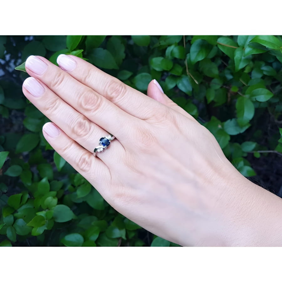 1.43 ct oval natural deep blue sapphire ring in 14K white gold with accent diamonds on a woman's hand.