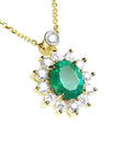 Close sight of a yellow gold necklace with a oval cut emerald gemstone in a halo diamond on a white background