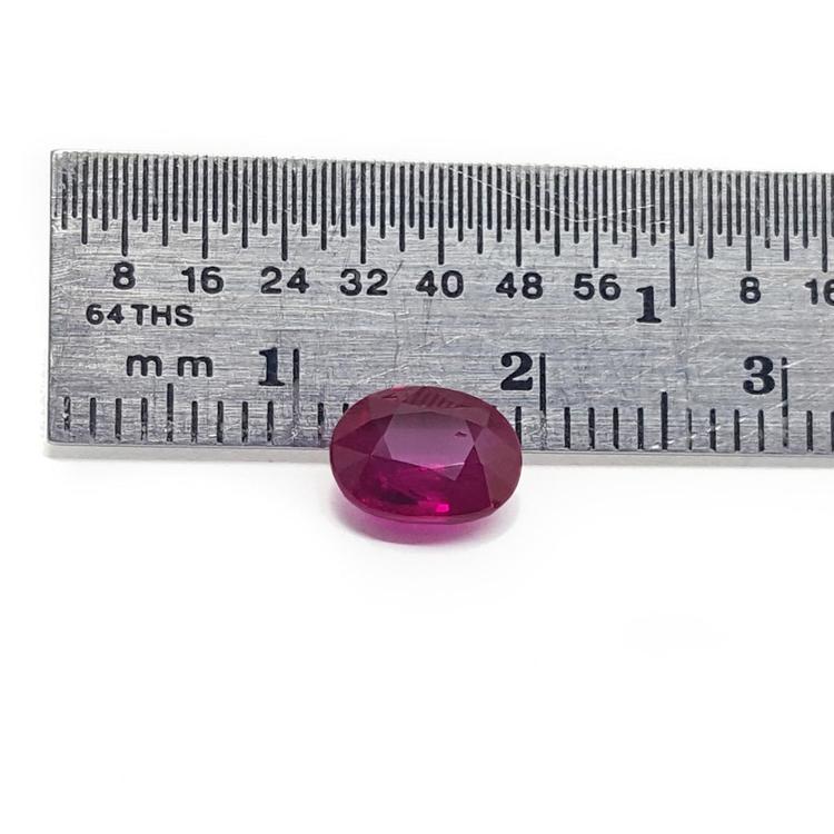 1.59 carat natural Burma ruby, oval cut, medium deep red, displayed next to a ruler.