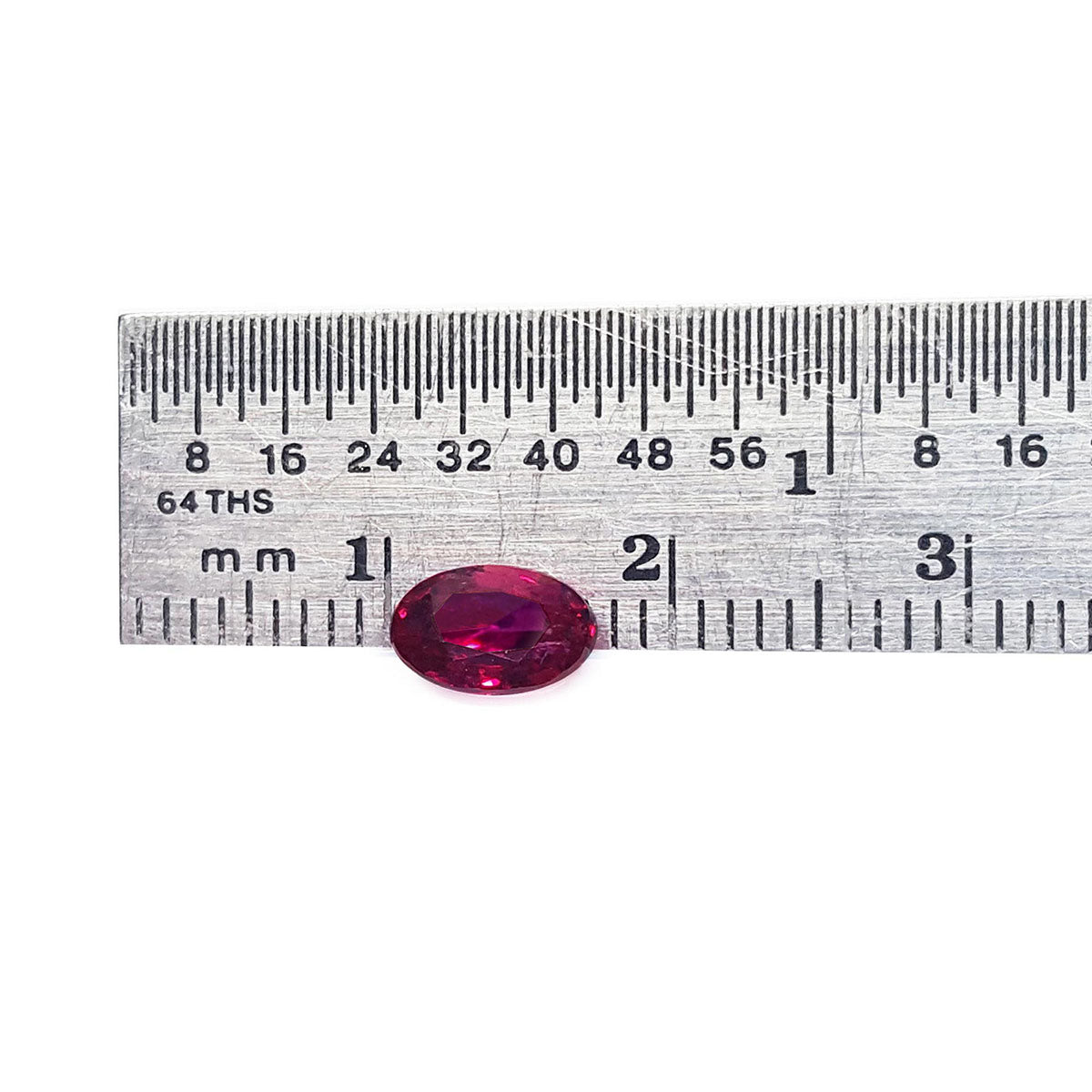 Oval cut loose natural ruby 0.91 ct. Burmese, front position table and crown visibles on a ruler for scale