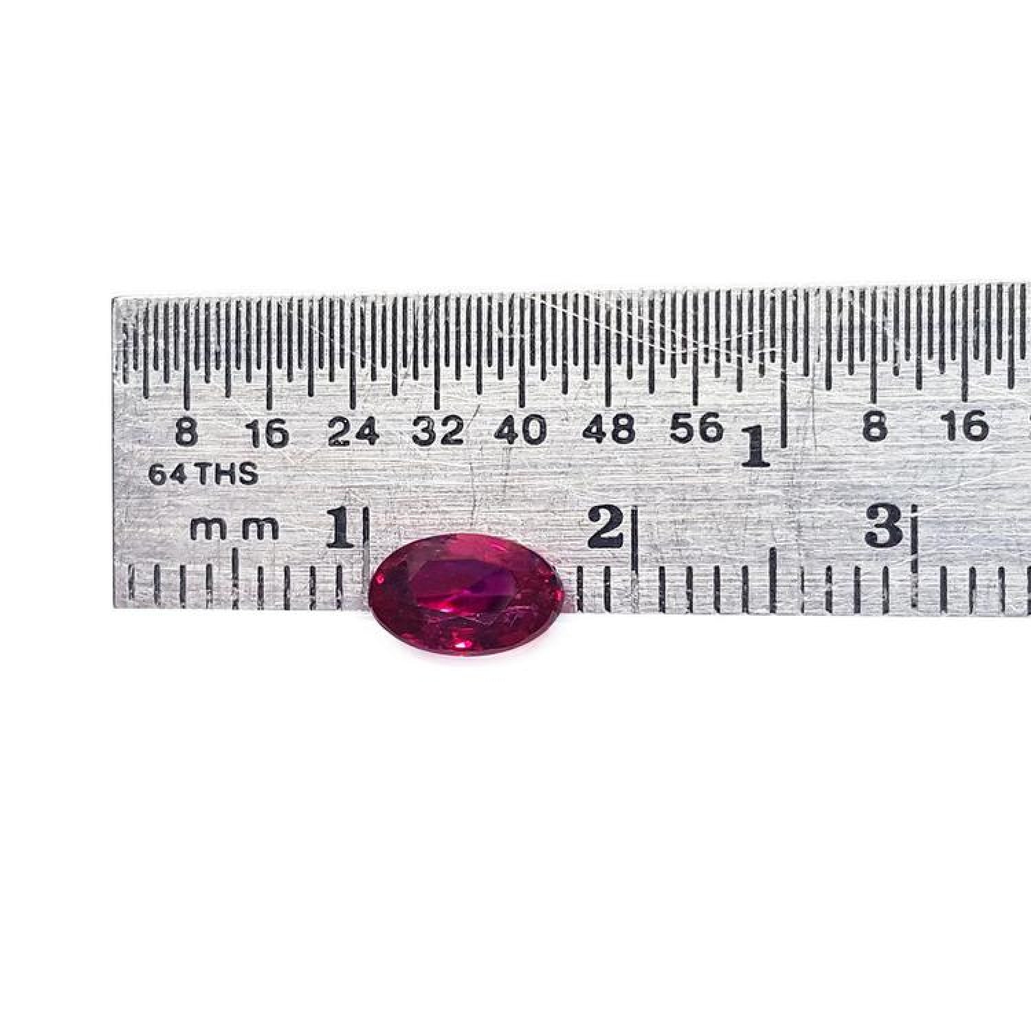 0.91 carat oval cut natural Burmese ruby with a vibrant medium deep red hue, shown next to a ruler.