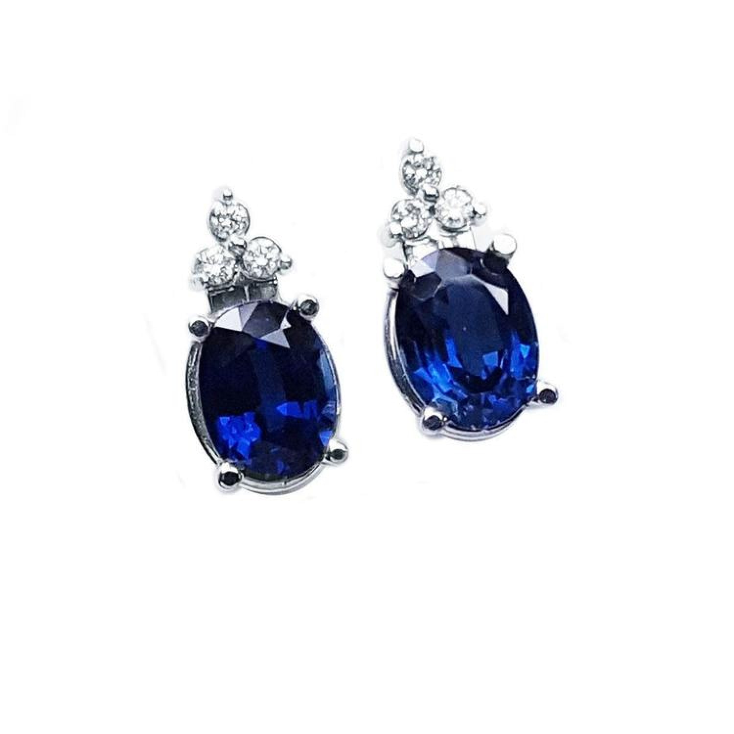 Oval deep blue sapphire stud earrings with three prong-set diamonds in 14K white gold.