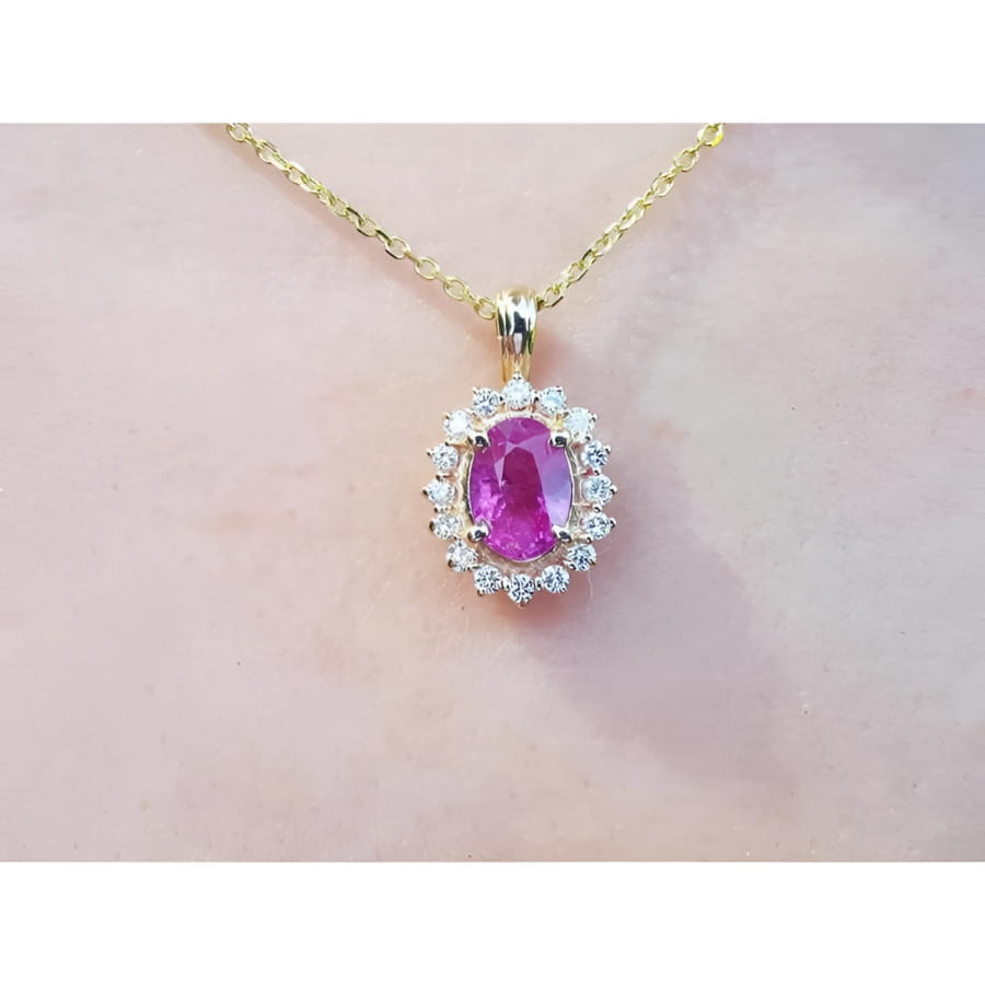 1.25 ct. oval pink sapphire halo diamond pendant on a 14K yellow gold chain.