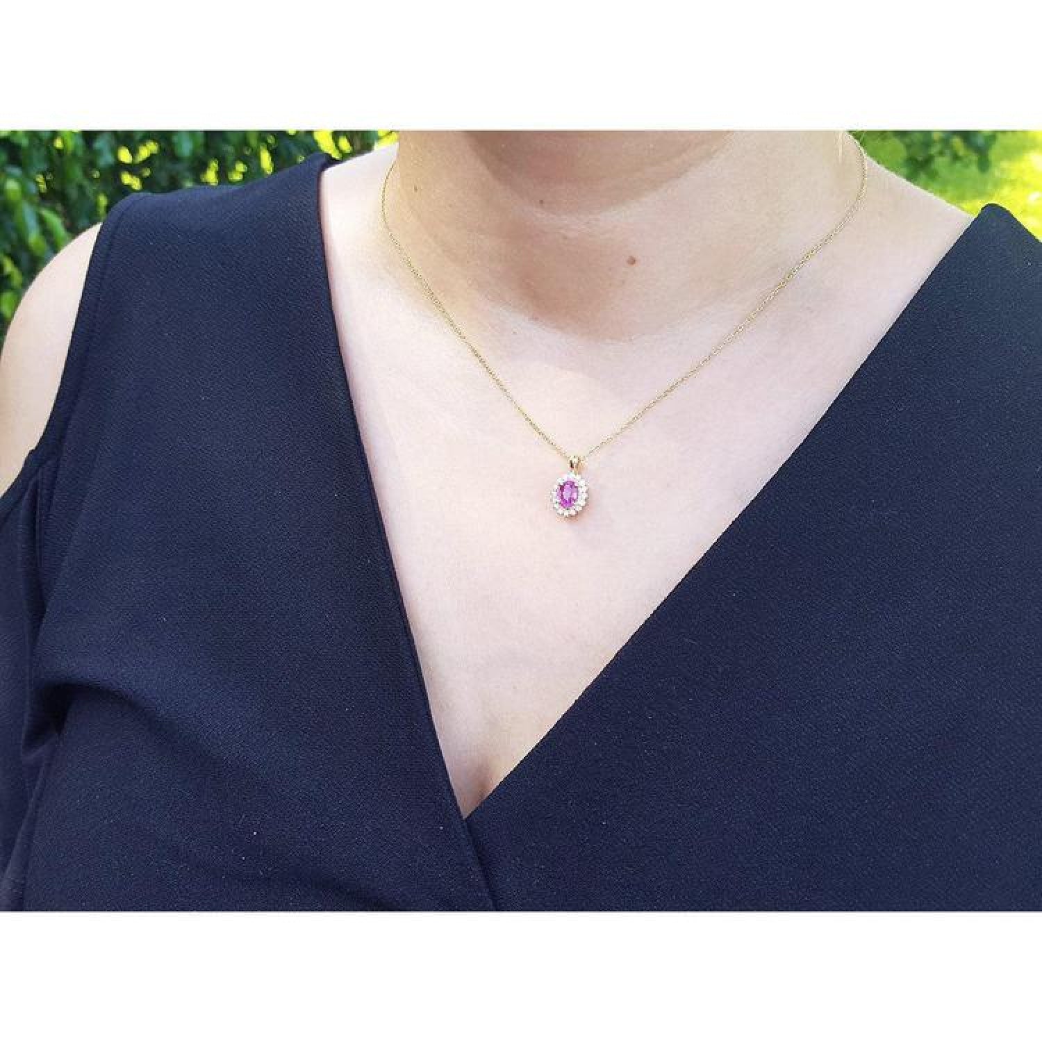 Oval pink sapphire halo diamond pendant necklace in 14K yellow gold on a model.