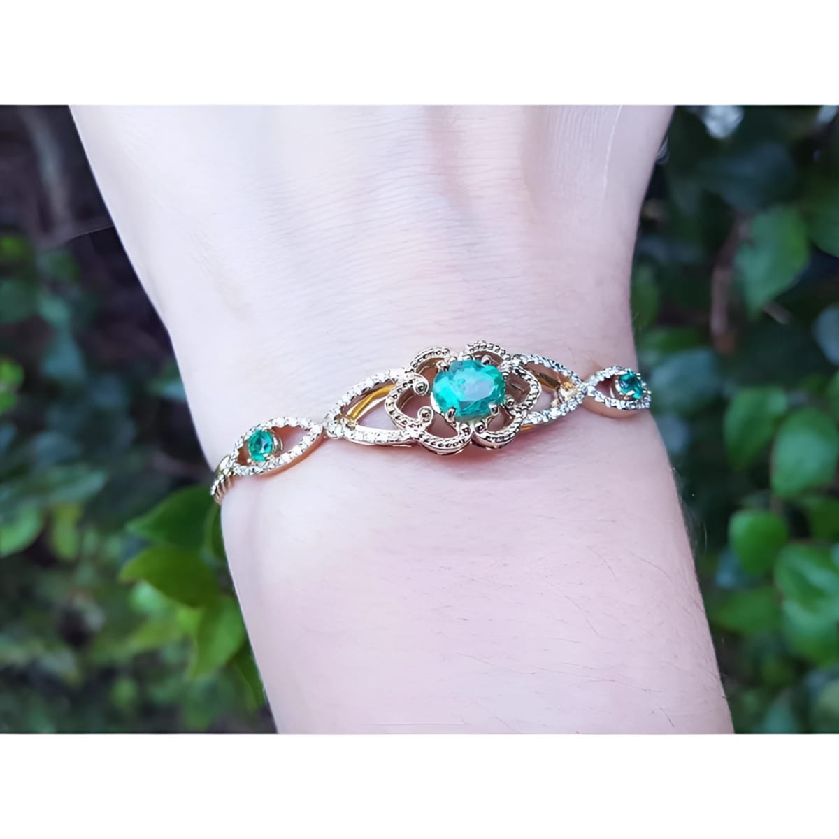 A women's bracelet with an oval cut natural colombian emerald and accent diamonds in 14k gold.