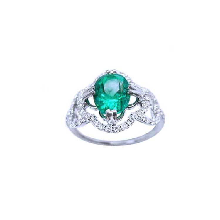 An oval cut Colombian emerald in the center of a clover ring design adorned with natural diamonds.