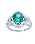 An oval cut Colombian emerald in the center of a clover ring design adorned with natural diamonds.