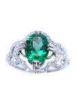 This oval-cut emerald, elegantly set at the heart of a four-leaf clover design framed by a halo of diamonds is in 14K gold.