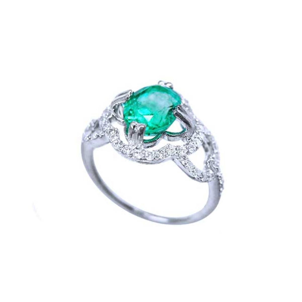A detailed view of an oval cut emerald centered in a clover ring design adorned with diamonds.