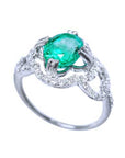 A detailed view of an oval cut emerald centered in a clover ring design adorned with diamonds.