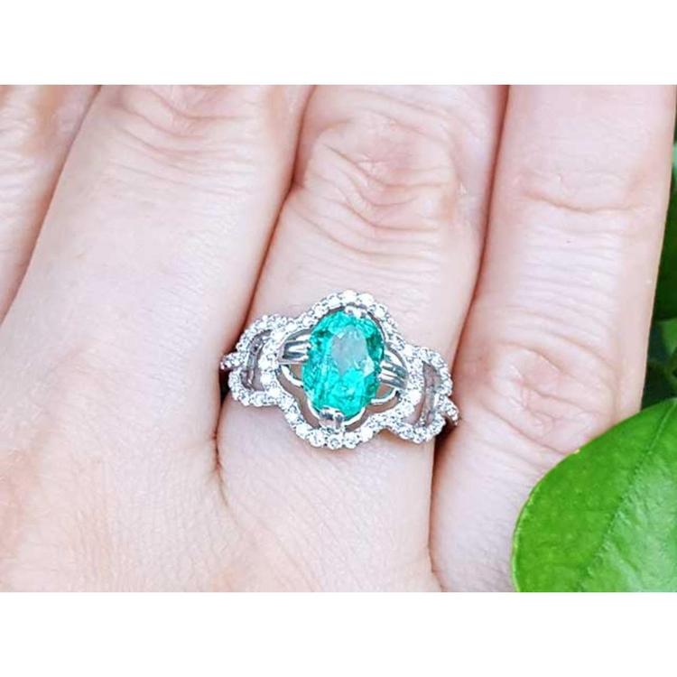Clover 14k white gold ring with an oval cut natural colombian emerald on a person's finger.