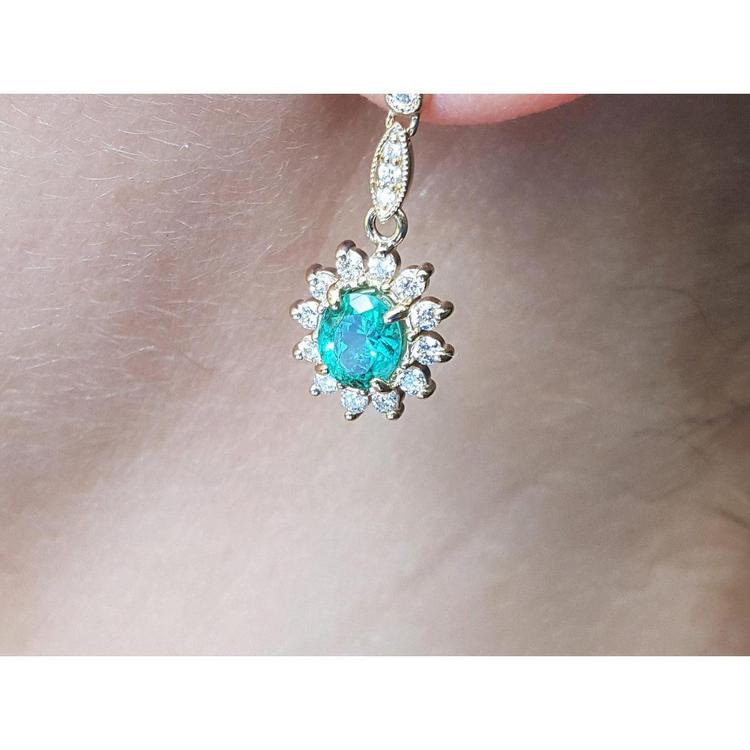 Close-up of a gold earring USA made Colombian emeralds on a person's ear.