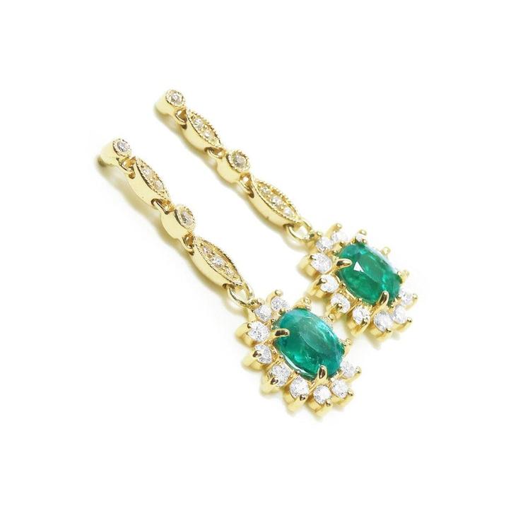 A pair of a 14k yellow gold with natural colombian emerald earrings with a halo diamond.