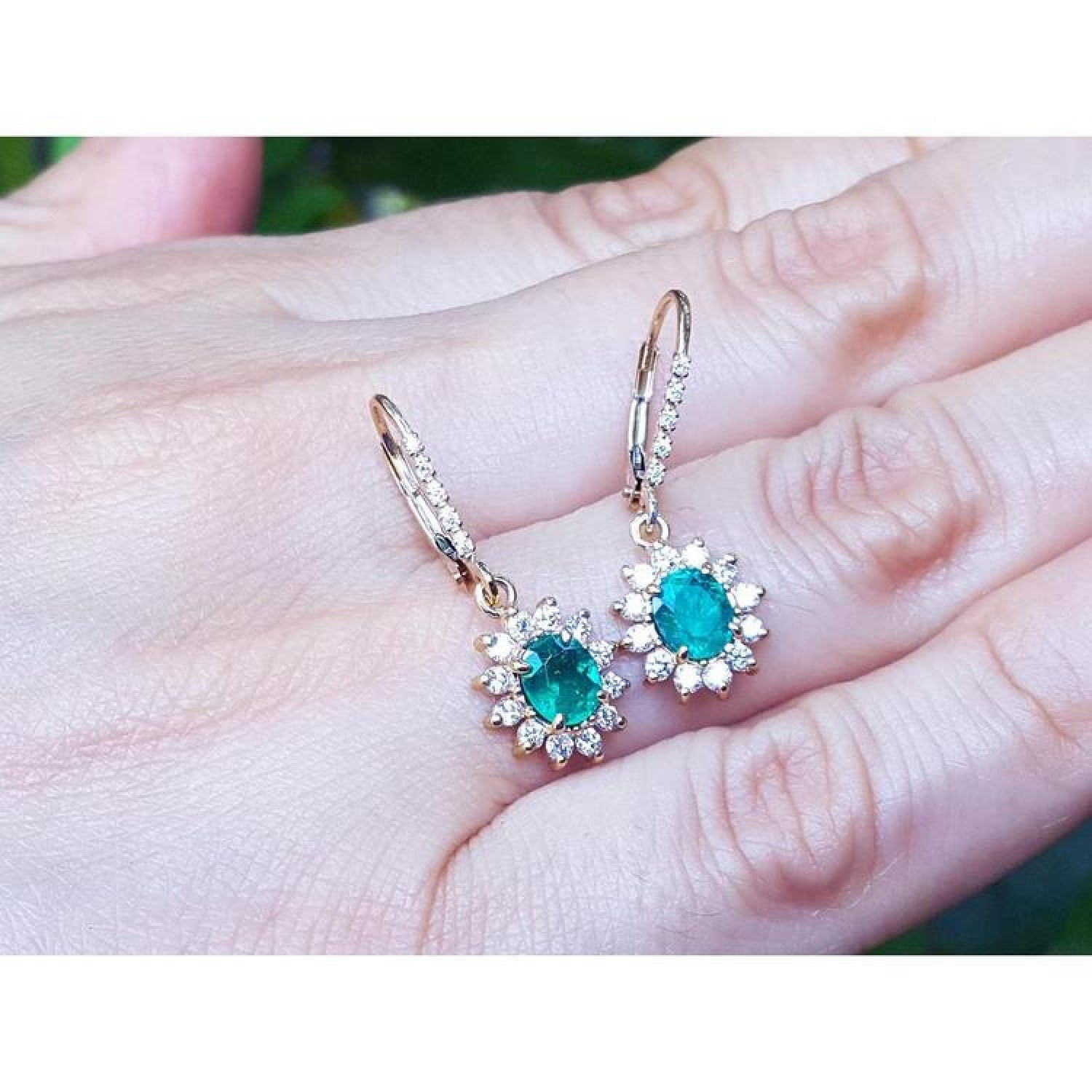1.09 carat oval cut emerald earrings with diamond halo, 14K gold lever backs.