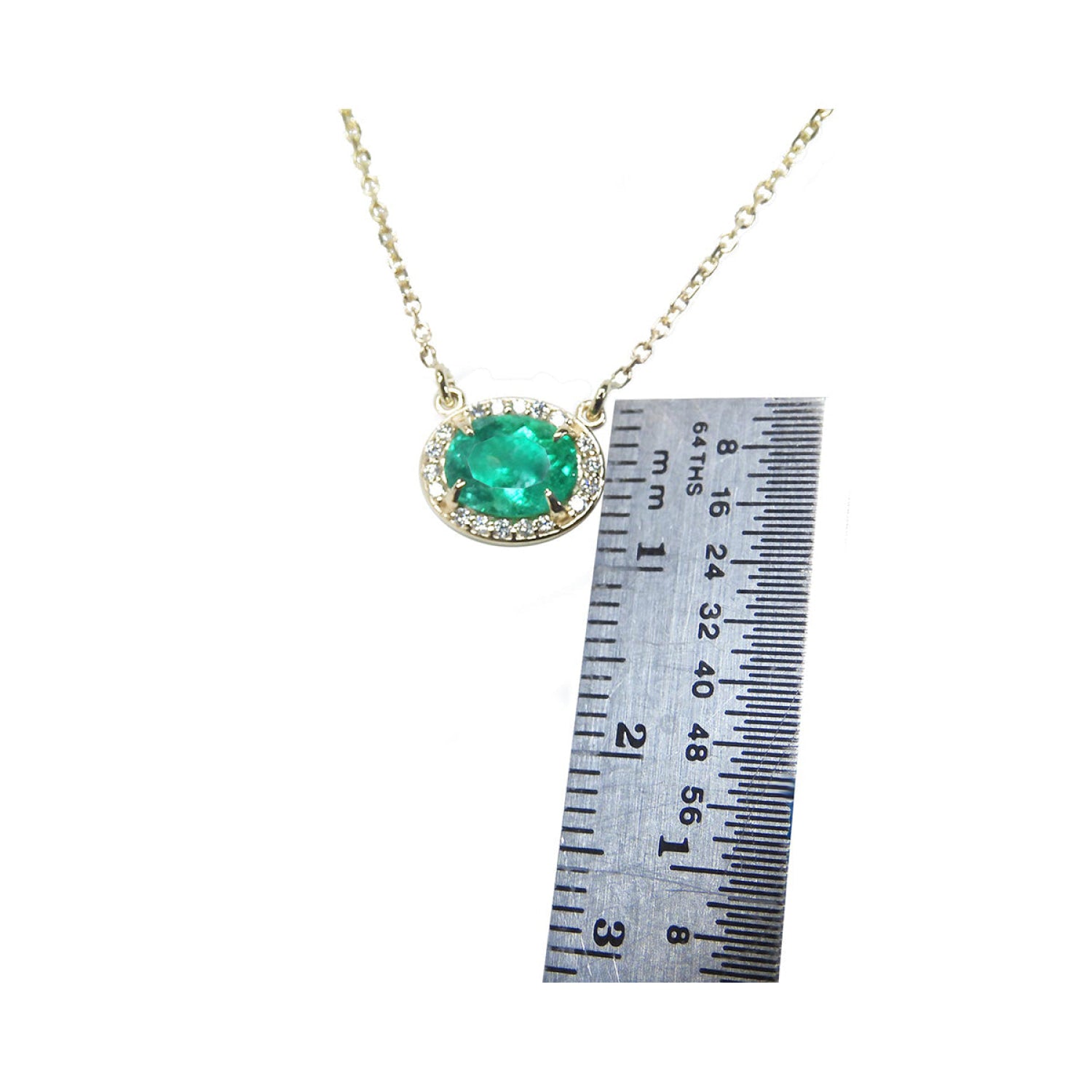 0.90 carat oval Muzo emerald necklace in 14K yellow gold, shown with a ruler for scale.