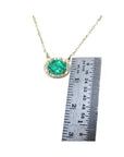 0.90 carat oval Muzo emerald necklace in 14K yellow gold, shown with a ruler for scale.