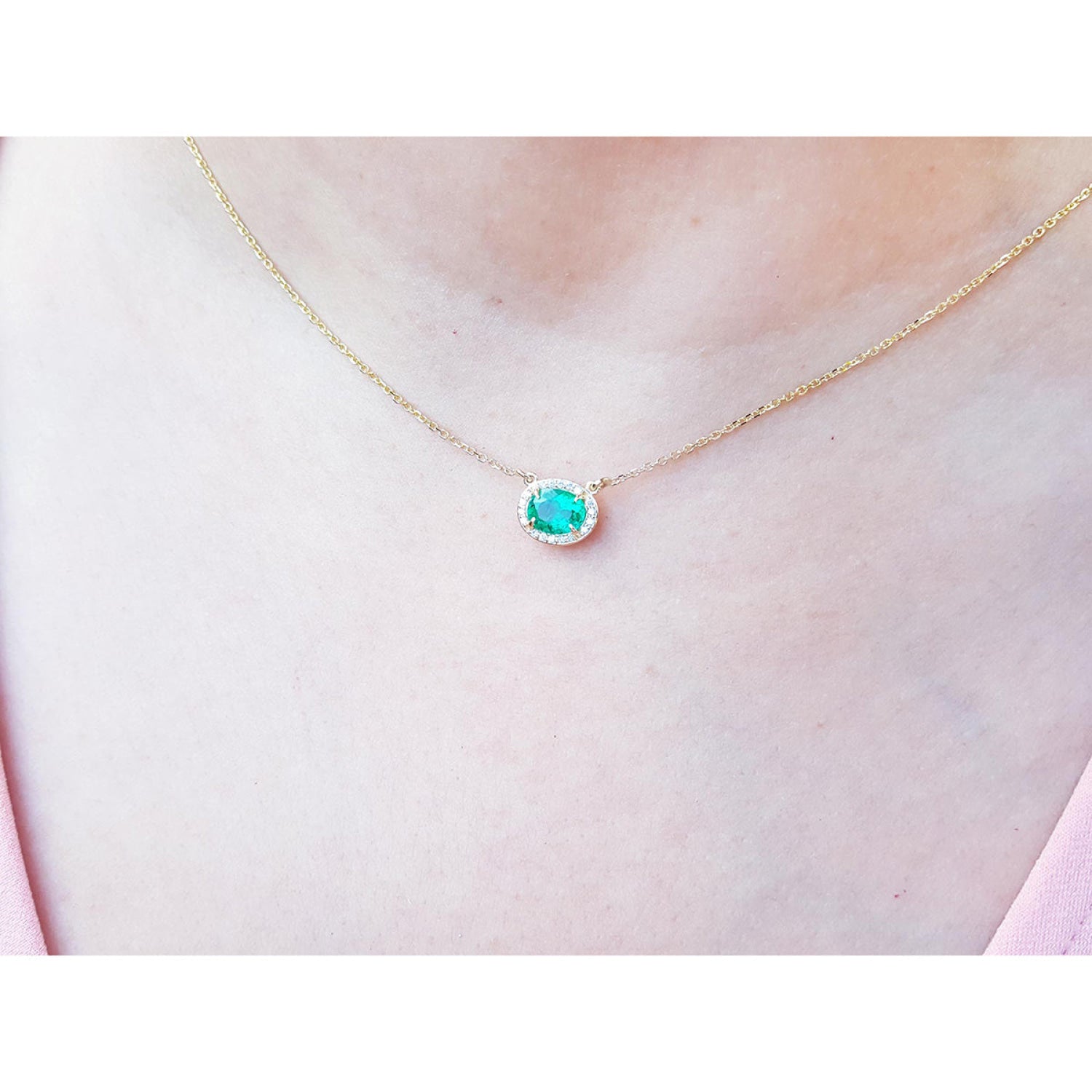 Oval Muzo emerald necklace with diamond halo on a delicate 14K yellow gold chain.