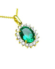 A 18k yellow gold pendant with an oval cut natural colombian emerald with a halo diamond, topside view.
