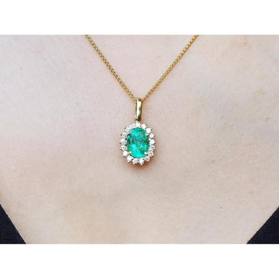 Oval 3.01 ct natural emerald pendant with halo diamonds on an 18K yellow gold chain.