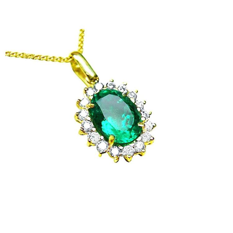 A 18k yellow gold pendant with an oval cut natural colombian emerald with a halo diamond, topside view.