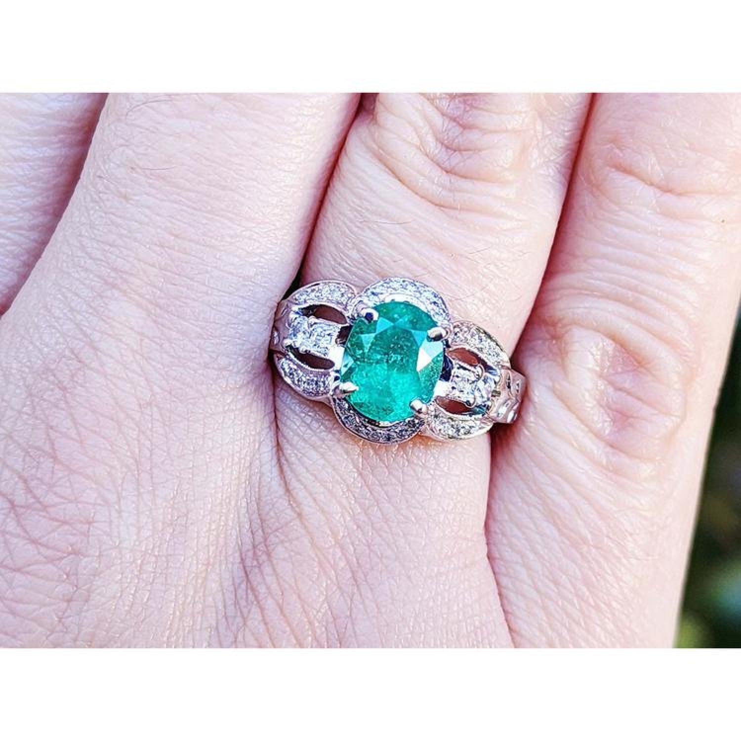 Natural oval emerald ring in 18K white gold with a decorative, bridal-style band.