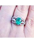 Natural oval emerald ring in 18K white gold with a decorative, bridal-style band.
