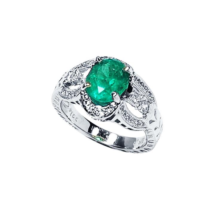 Natural oval emerald ring in 18K white gold with a decorative, diamond-accented band.