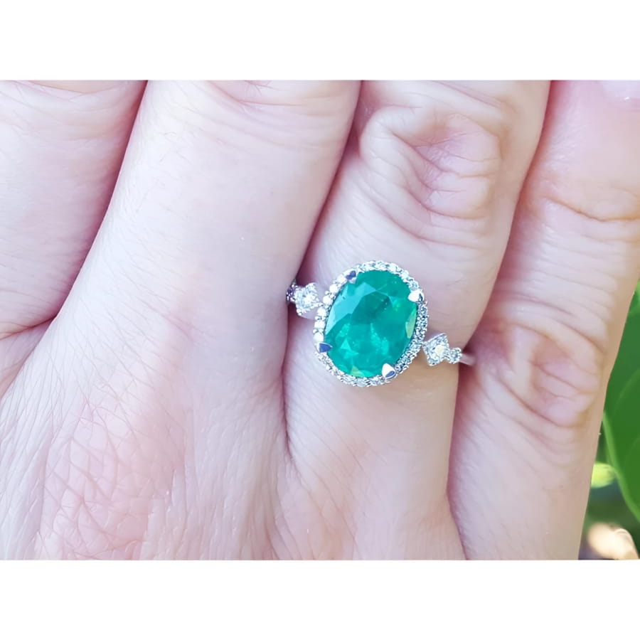 14K white gold halo ring with a 2.02 ct. oval-cut deep green emerald and natural diamonds.