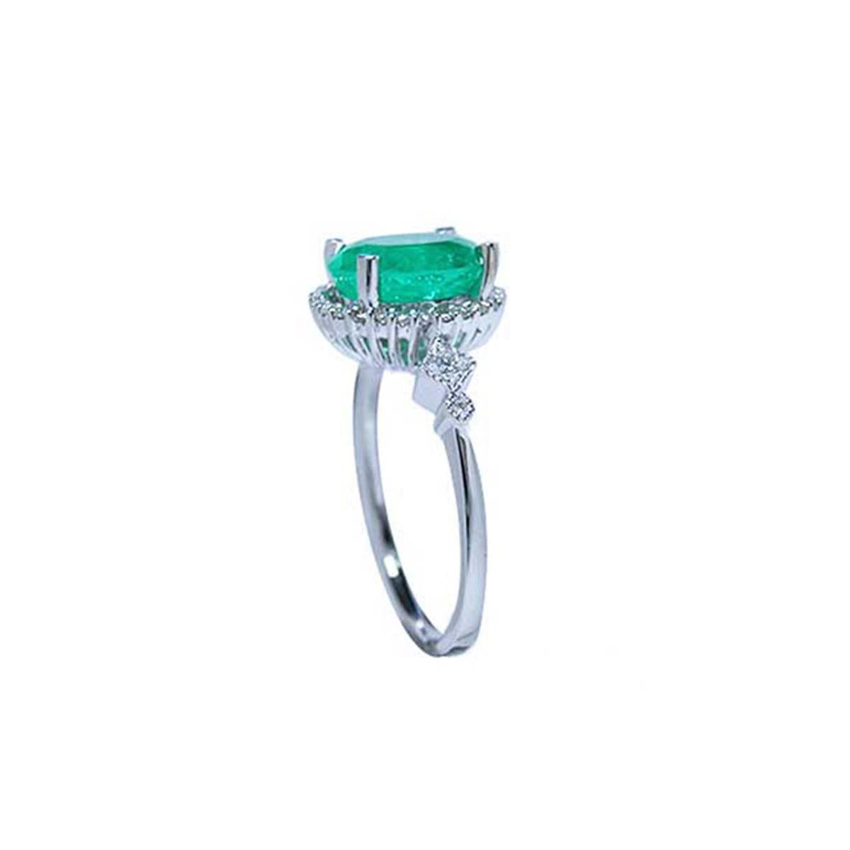 An emerald ring displaying the top side gallery and band with accent diamonds.