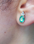 Closeup view of an oval cut emerald earring on an earlobe of a woman ear
