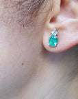 Muzo emerald earrings on a woman's ear
