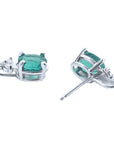 A pair of emerald earrings ocal cut white gold in upside down positions underside view