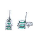 Two oval cut emerald earrings in white gold upside down position to see underside details