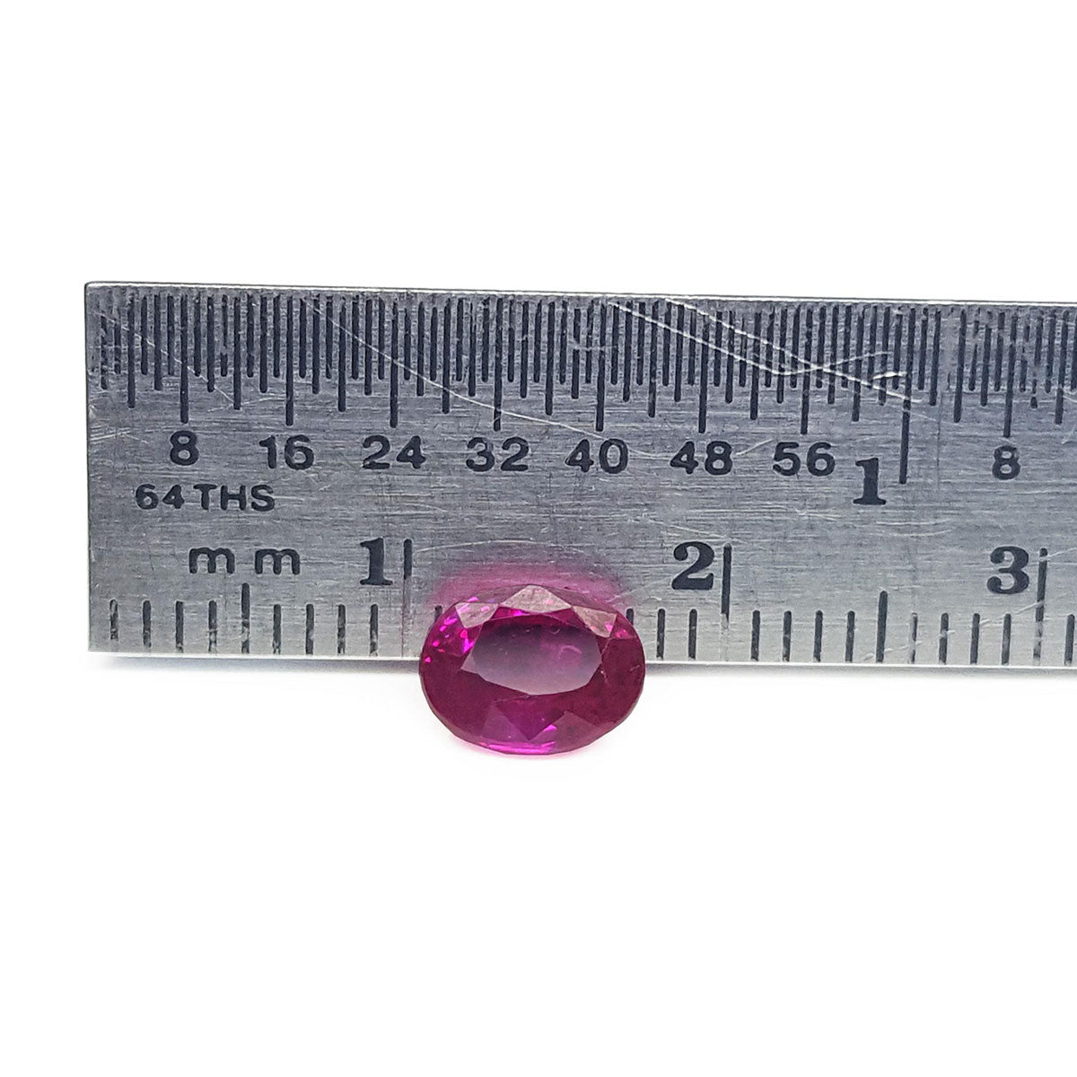 Oval cut ruby loose natural gemstone from Burma, front side crown and table visibles on a ruler for scale