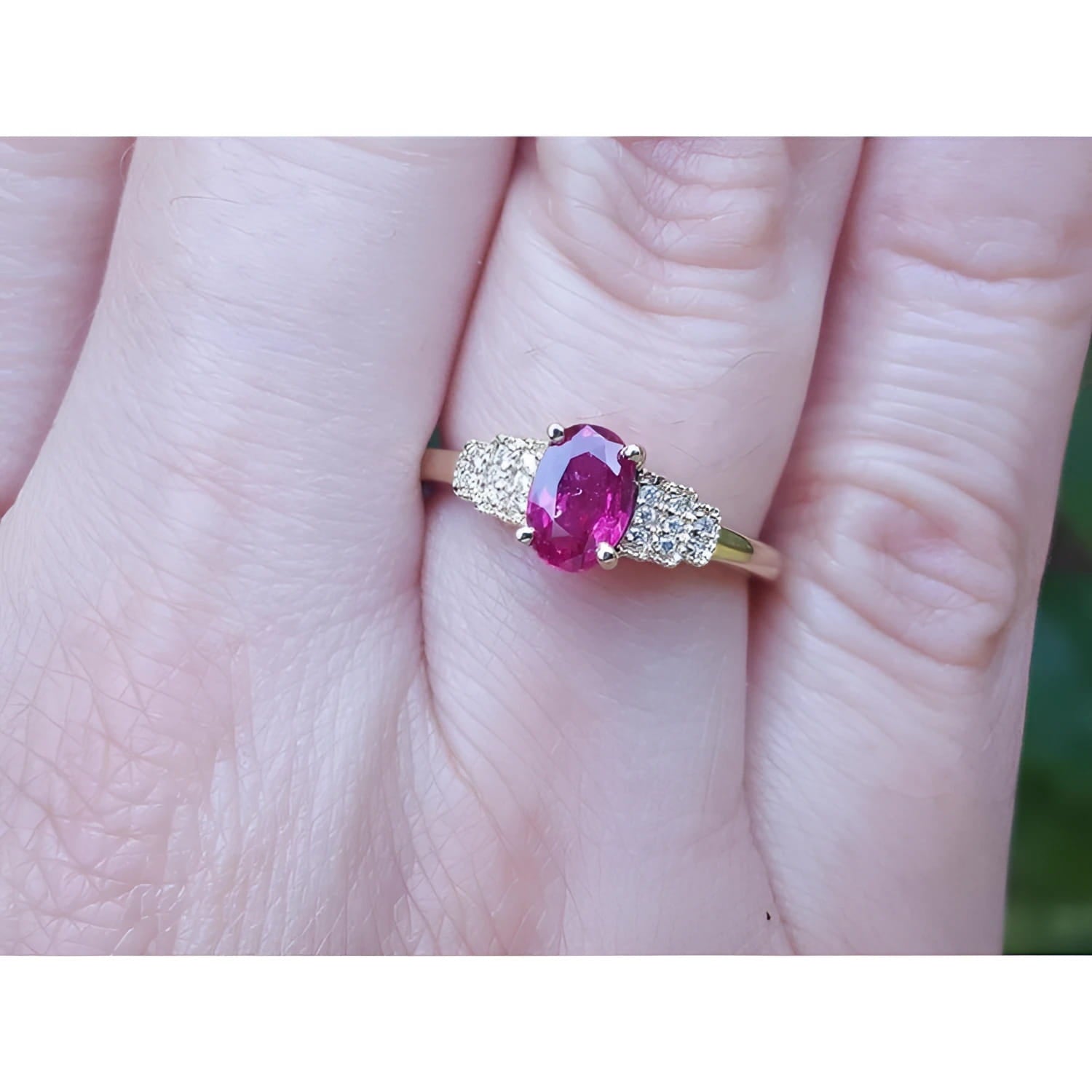 Women's 14k yellow gold ring with a deep red oval ruby and sparkling side diamonds.