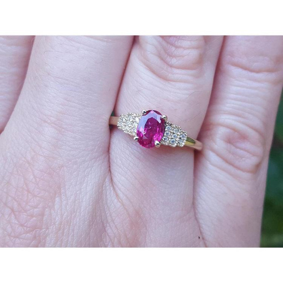 Women's 14k yellow gold ring with a deep red oval ruby and sparkling side diamonds.