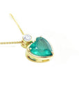 Heart-shaped emerald pendant in 18K yellow gold with a slider bail and bezel-set diamond.