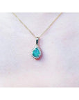 Pear-shaped Colombian emerald pendant with halo diamonds on a 14K yellow gold chain.