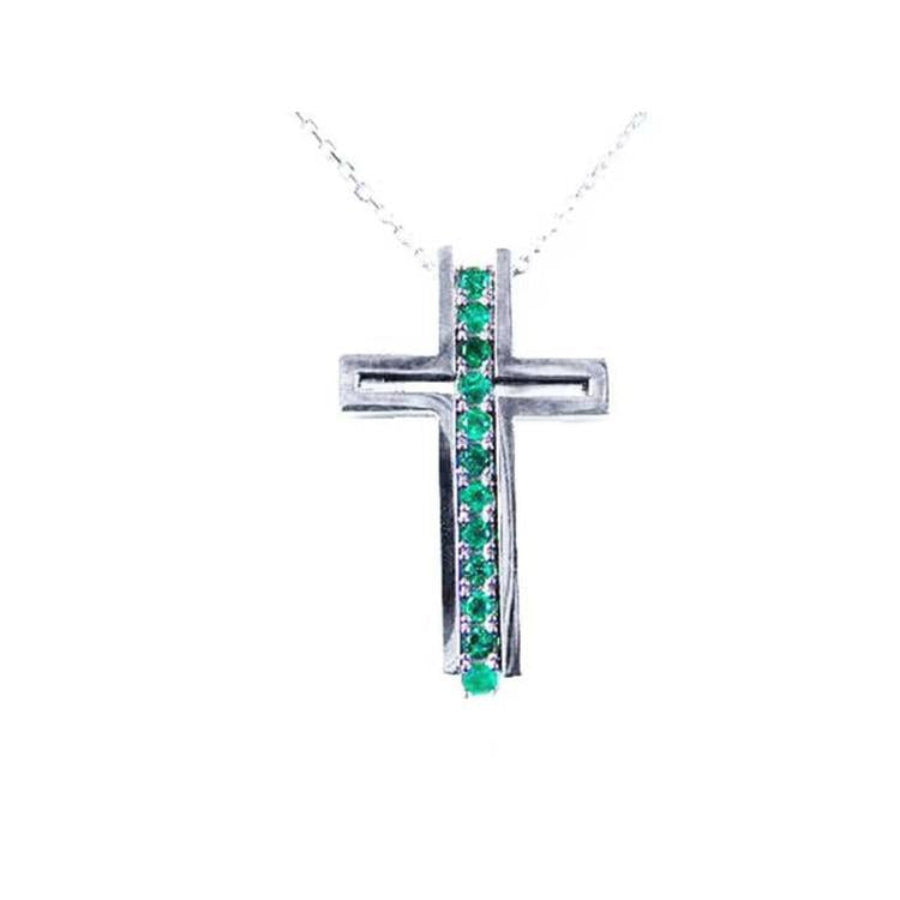 14K white gold cross pendant with a vertical row of round cut Colombian emeralds.
