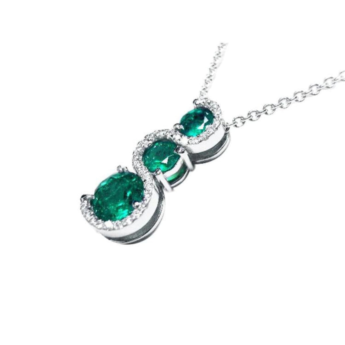 14K white gold journey pendant with three round-cut Colombian emeralds and diamond accents on a chain.