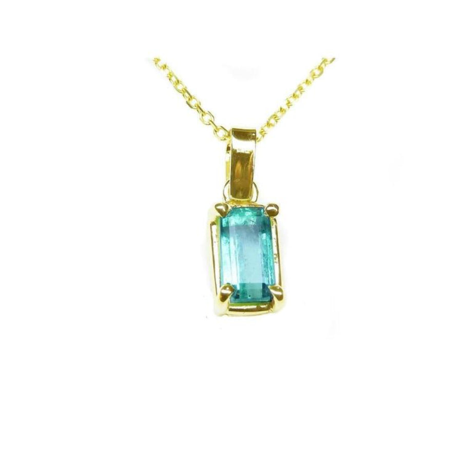 This solitaire colombian emerald pendant displays the topside with a 14k yellow gold frame on a chain.