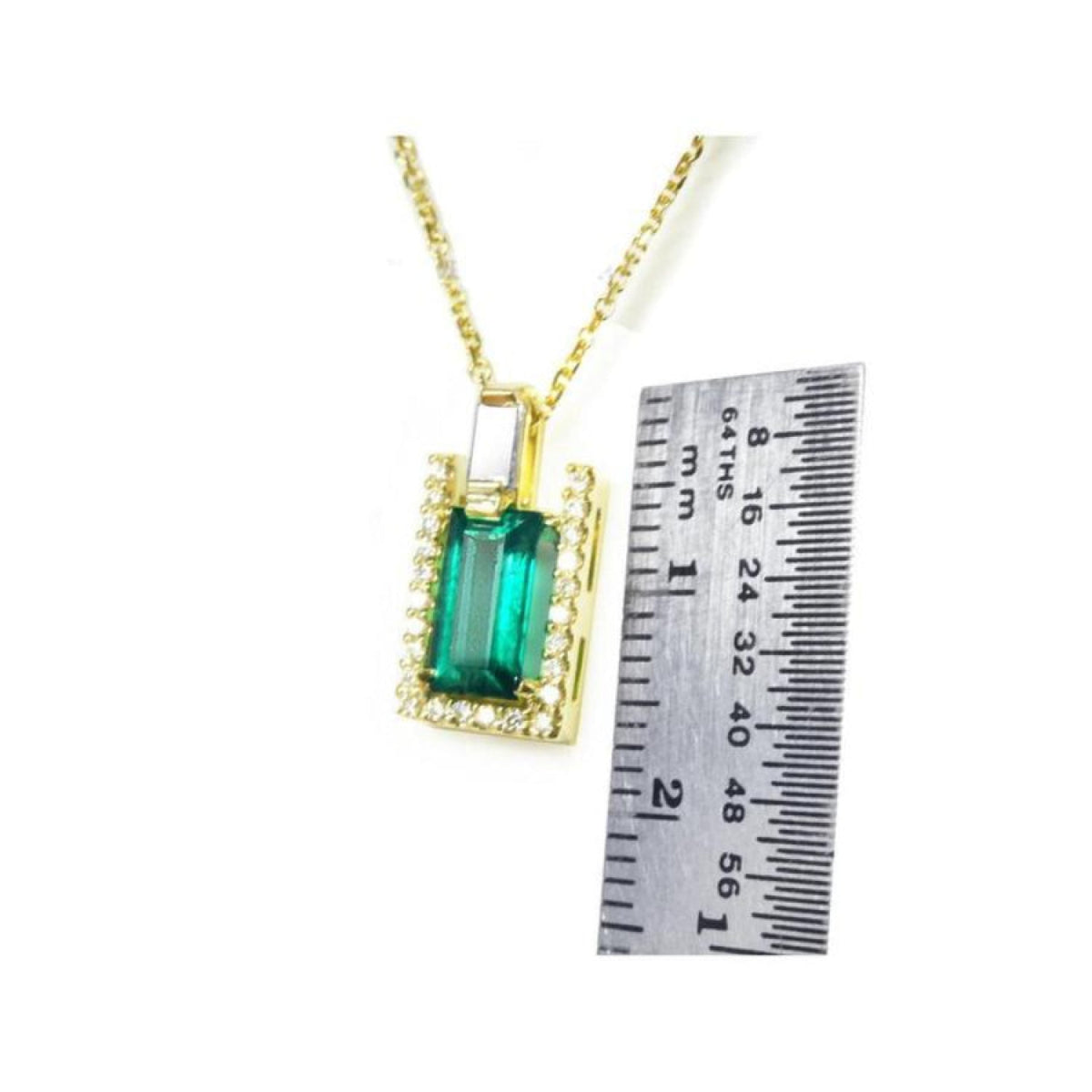 1.14 ct baguette emerald pendant with diamond bail, set in 14K yellow gold, next to a ruler.