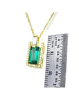 1.14 ct baguette emerald pendant with diamond bail, set in 14K yellow gold, next to a ruler.
