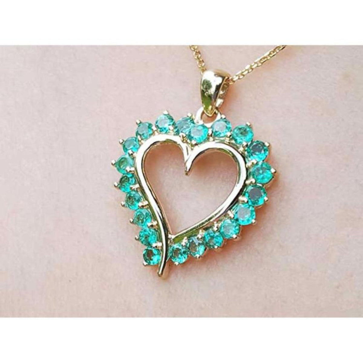 Heart-shaped pendant with round cut colombian emerald stones made of 14k yellow gold.