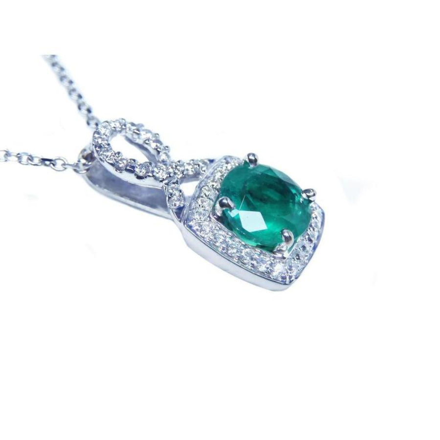 Round emerald and diamond halo pendant in 18K white gold with a deep bluish-green gemstone.