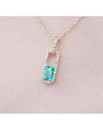 18k yellow gold necklace with a natural emerald pendan surrounded by a halo diamond.