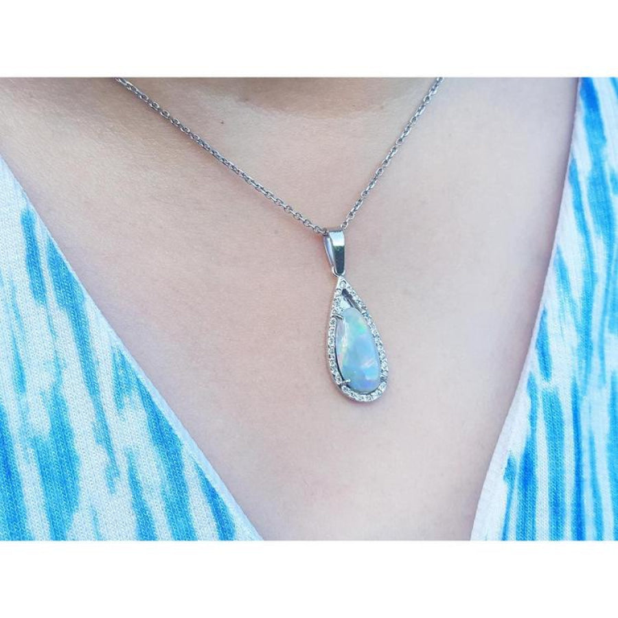 Pear-shaped Australian opal pendant with halo diamonds on an 18K white gold chain, worn on a person.
