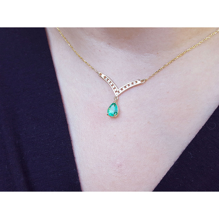 Natural pear shaped emerald necklace, is dangling from a channel set diamonds chevron design in 14k yellow gold